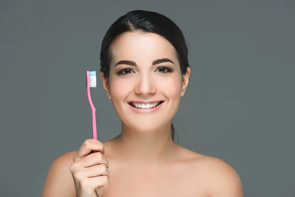 Person holding a toothbrush and smiling.