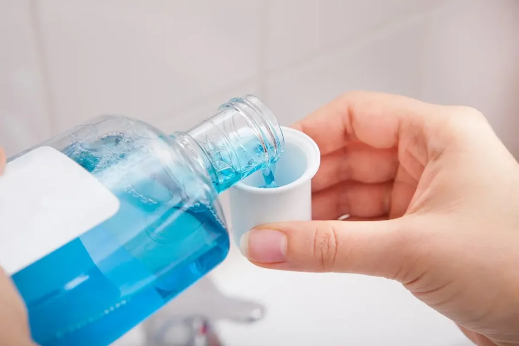 Blue mouthwash being poured into a small cup.