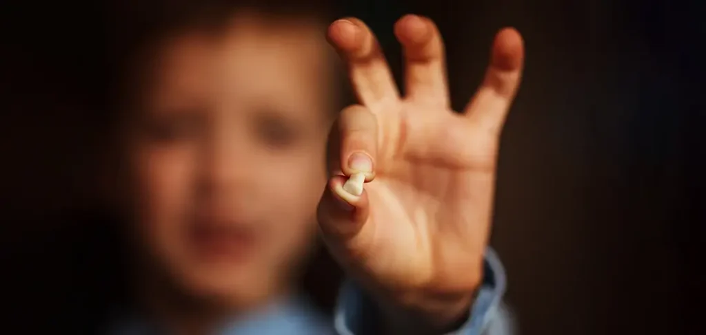 Child holding a tooth.