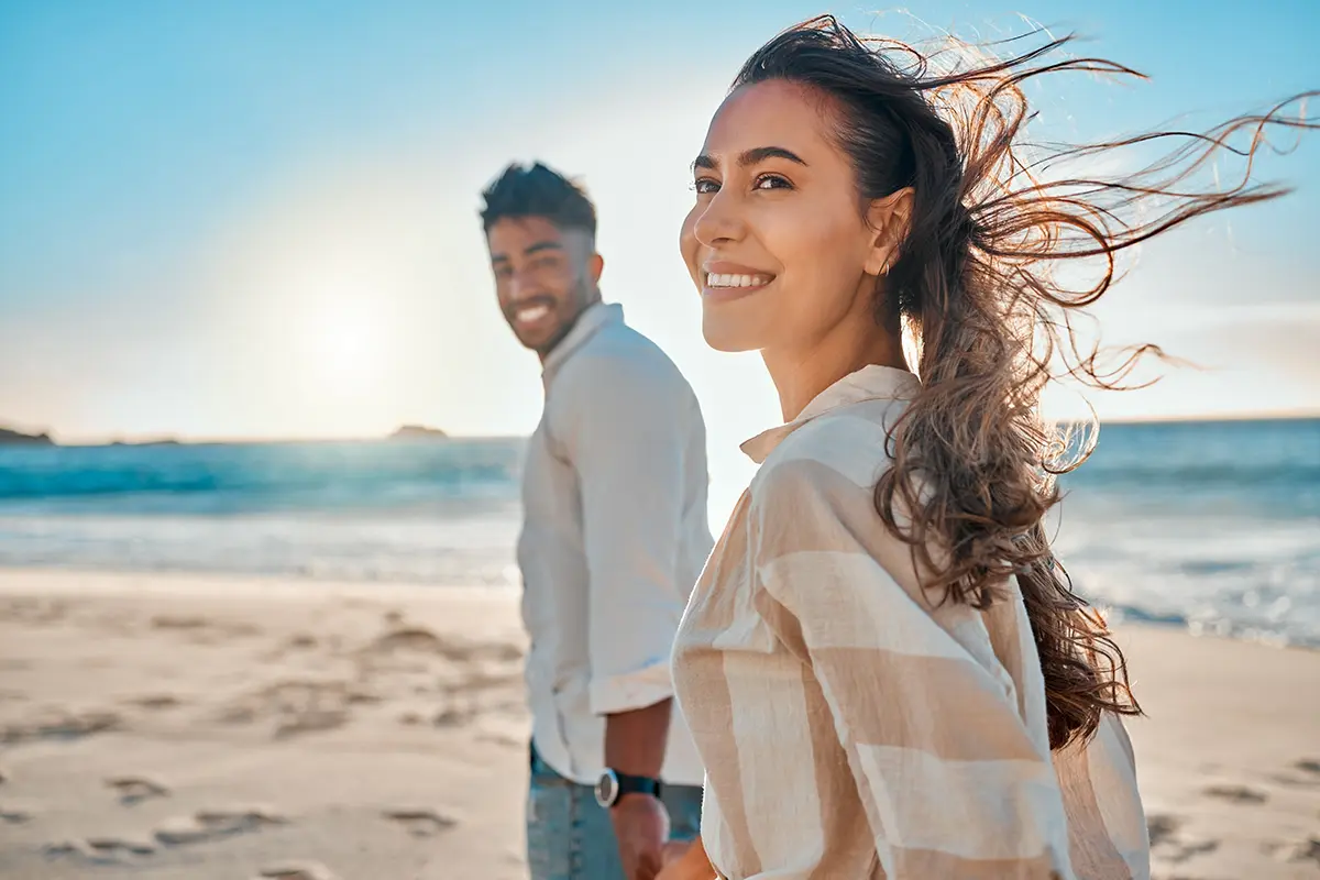 Smiling couple walking on a beach as part of their summer vacation