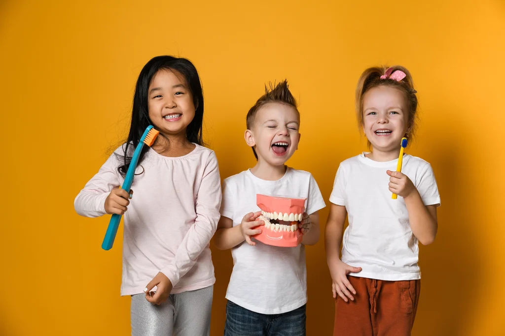 Children holding toothbrushes and laughing