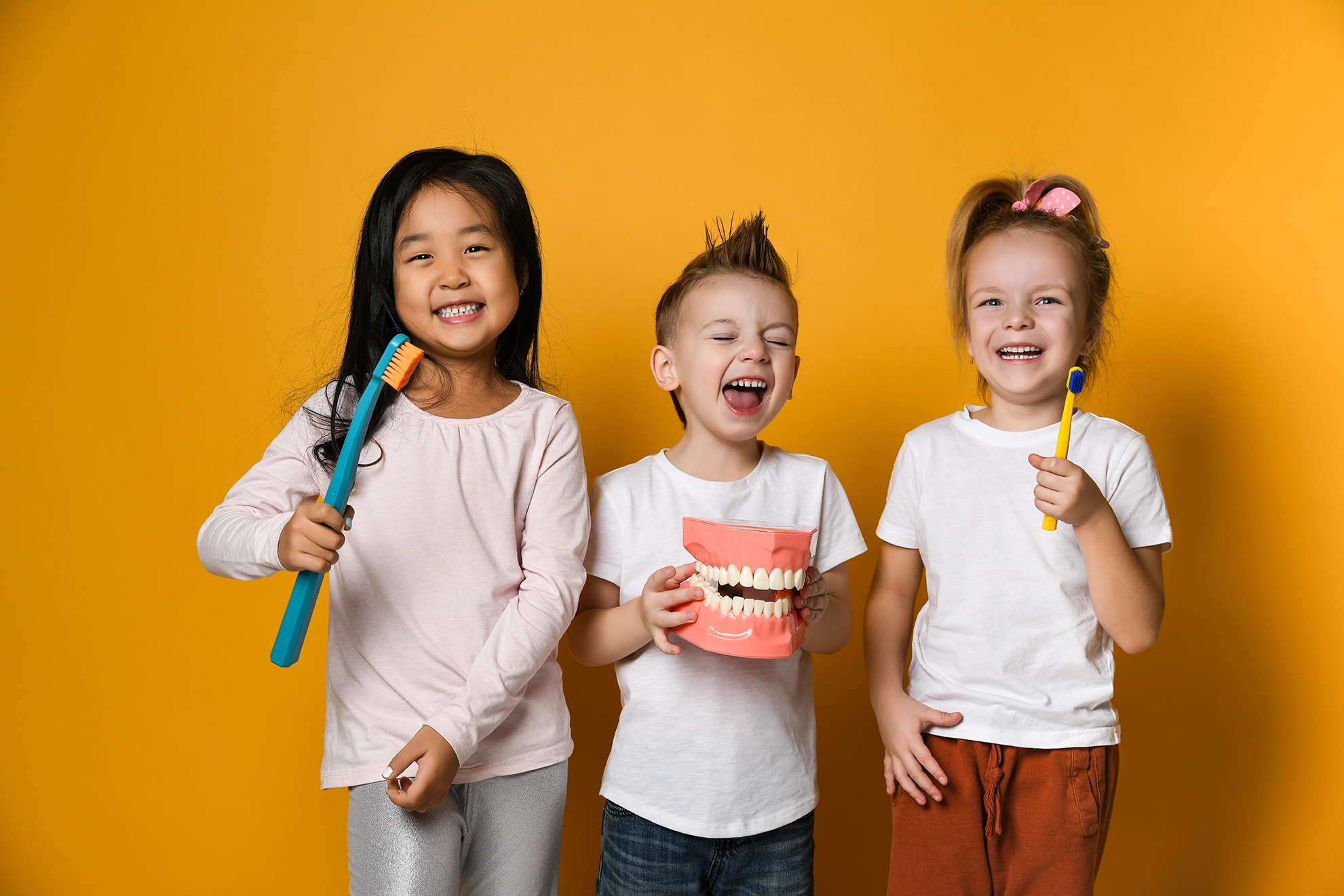 Children holding toothbrushes and laughing