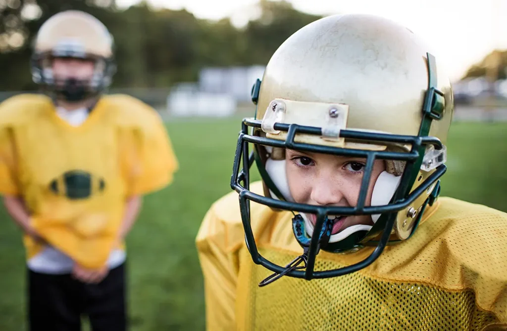 Two teenage football players with helmets and mouthguards